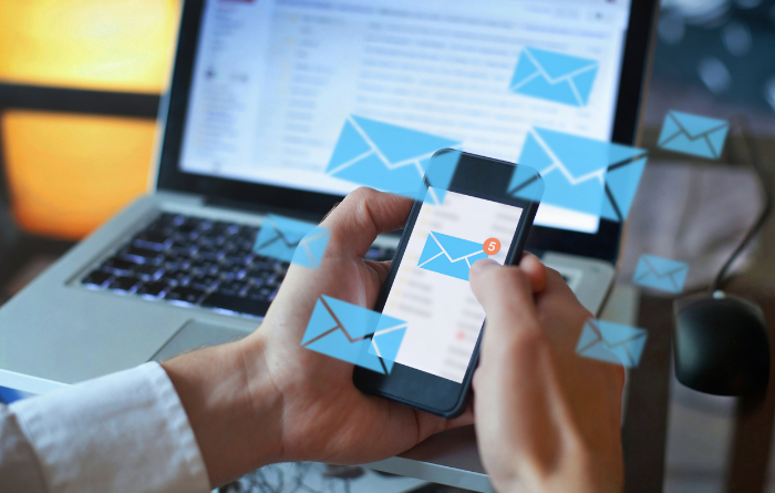 Man using phone to check emails in front of laptop